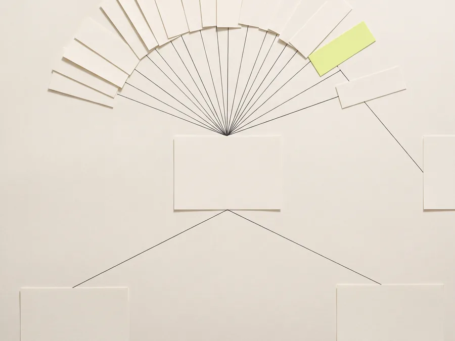 A fan of blank paper slips converging by fine ink lines into one card, with a single lime slip taking its own branch away.